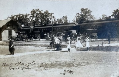 Historical photograph captioned Scene at Soo Line Station Grays Lake Ill, horse-drawn wagons, passengers gathered on platform, early 1900s